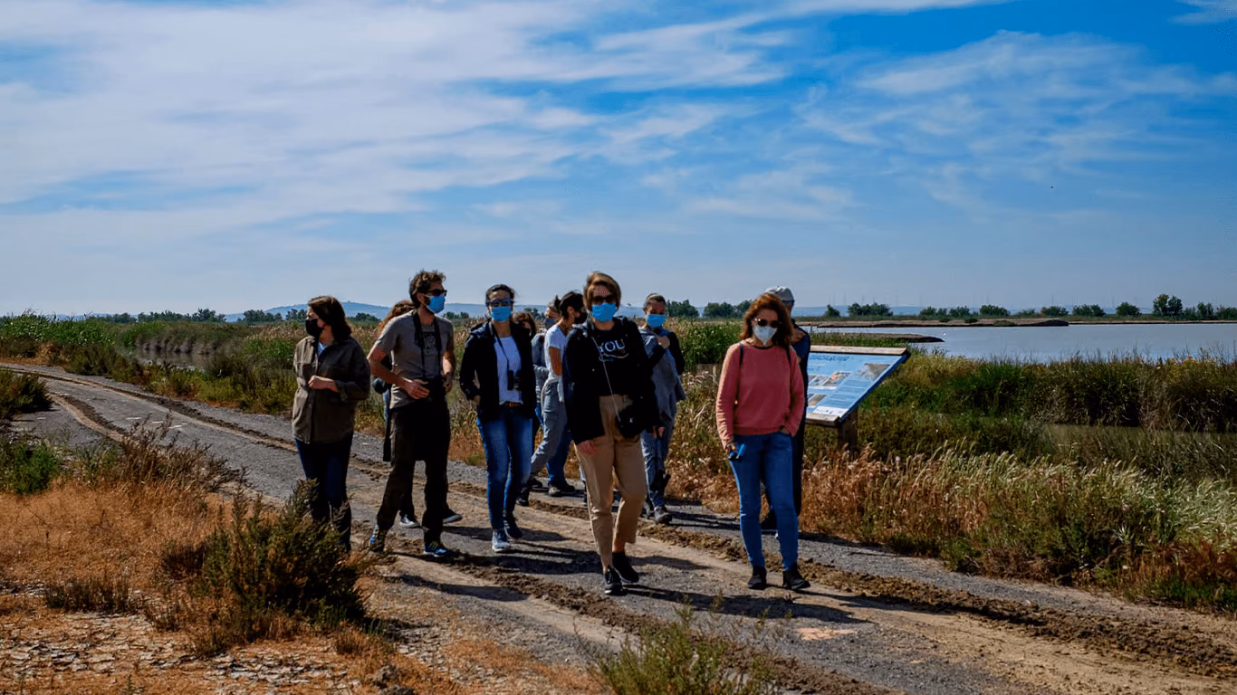 Visitantes caminando por un sendero junto a los esteros, con el agua al fondo